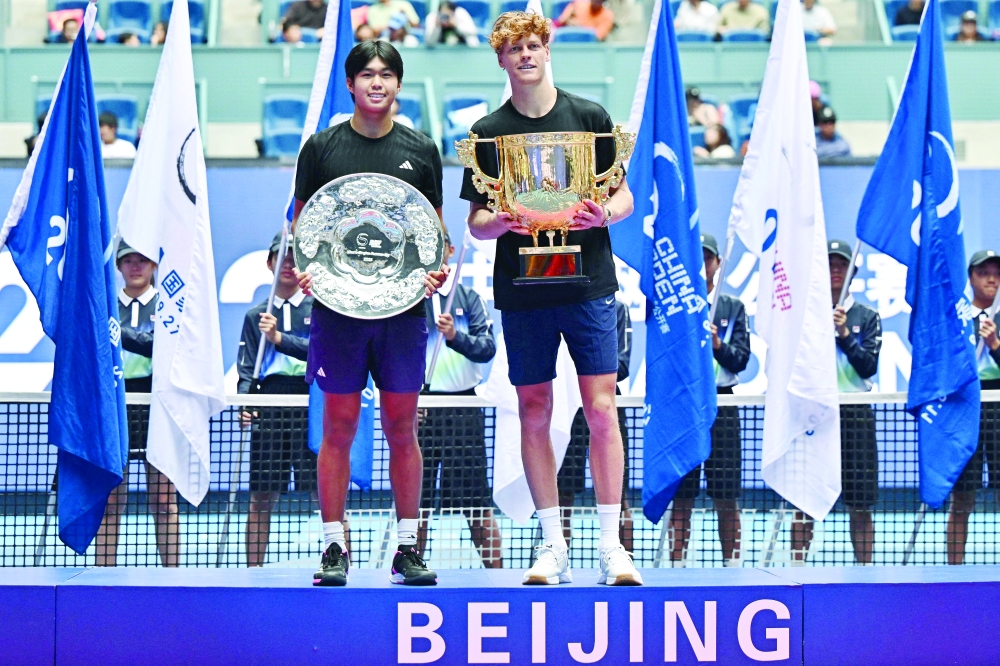 Italy's Jannik Sinner (R) holds his winner's trophy while posing with runner-up USA's Learner Tien following their men's singles final at the China Open tennis tournament in Beijing. — AFP