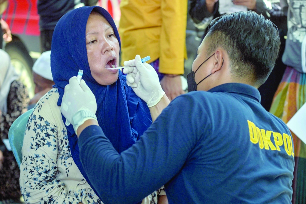 A police post-mortem officer takes a DNA sample from a relative of one of the missing students as rescuers search for survivors at the Al Khoziny Islamic boarding school in Sidoarjo, East Java province, after a multi-storey building at the school collapsed.- AFP