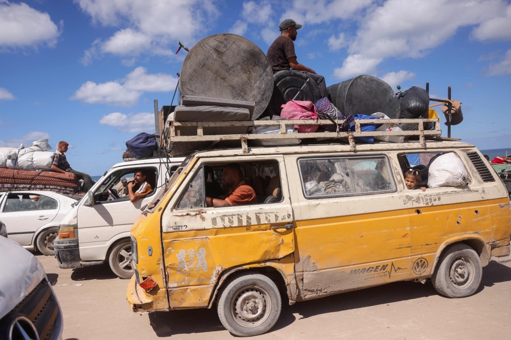 Palestinians carrying belongings arrive on a coastal path northwest of Nuseirat refugee camp as they are displaced southward from Wadi Gaza following an Israeli announcement of closing Al-Rashid road towards the north of the besieged Gaza Strip on October 1, 2025. Israel's defence minister issued a final warning for Gaza City residents to flee south on October 1