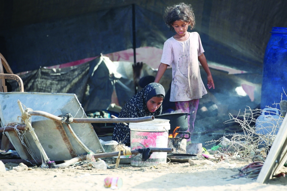 Displaced Palestinian girls light a fire under a pot outside their family's tent near a coastal path northwest of Nuseirat refugee camp after being displaced southward following an Israeli announcement of closing Al Rashid road towards the north of the besieged Gaza Strip on October 4, 2025. Israel said on October 4, that its troops were still operating in Gaza and warned residents not to return, despite calls from the families of Israeli hostages and US President Donald Trump for an immediate halt to the fighting. 