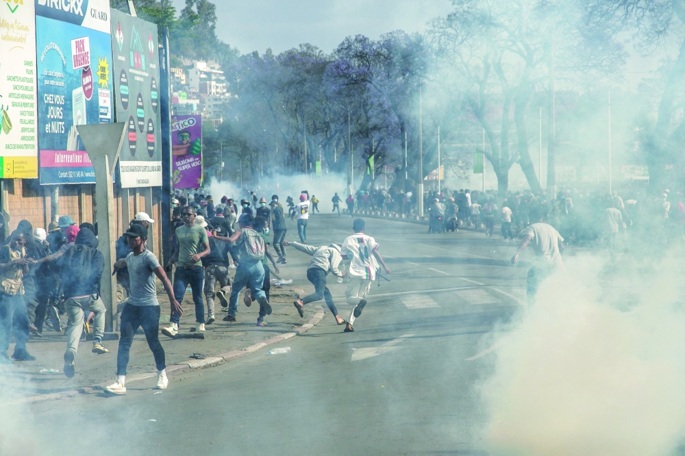 Protesters run for cover after security forces fired tear gas canisters, in Antananarivo. — AFP