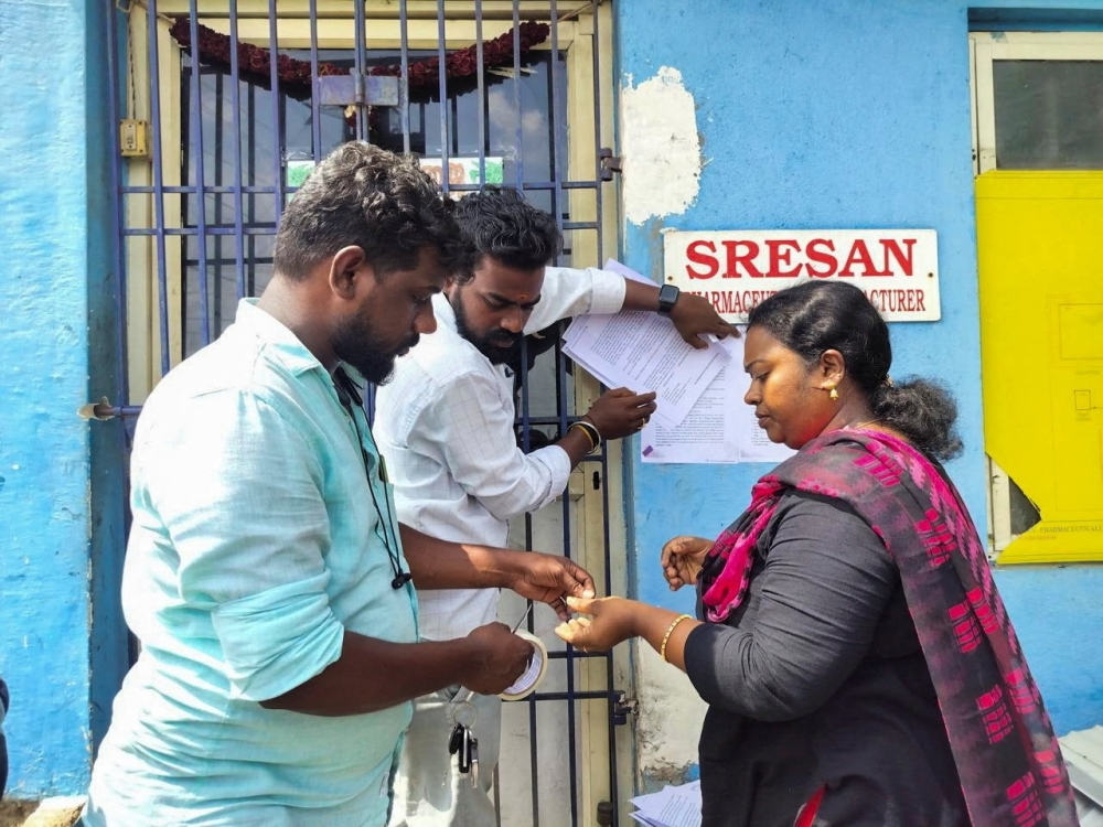 An official sticks a notice outside the Sresan Pharmaceutical factory whose Coldrif cough syrup has been linked to the deaths of 17 children. — Reuters