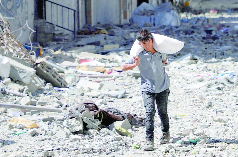 Palestinian boy carries a bag with flour at Sabra neighbourhood, following Israeli operation, in Gaza City, on Wednesday. — Reuters