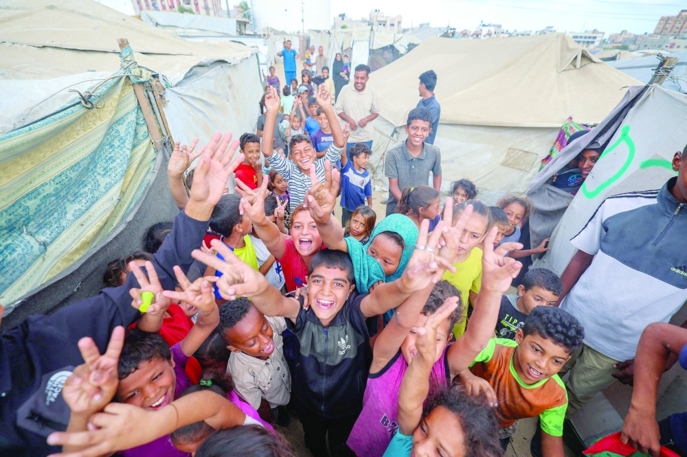 Palestinian children celebrate at a camp for displaced people in Nuseirat in the central Gaza Strip on Thursday, following news of a new Gaza ceasefire deal. - AFP