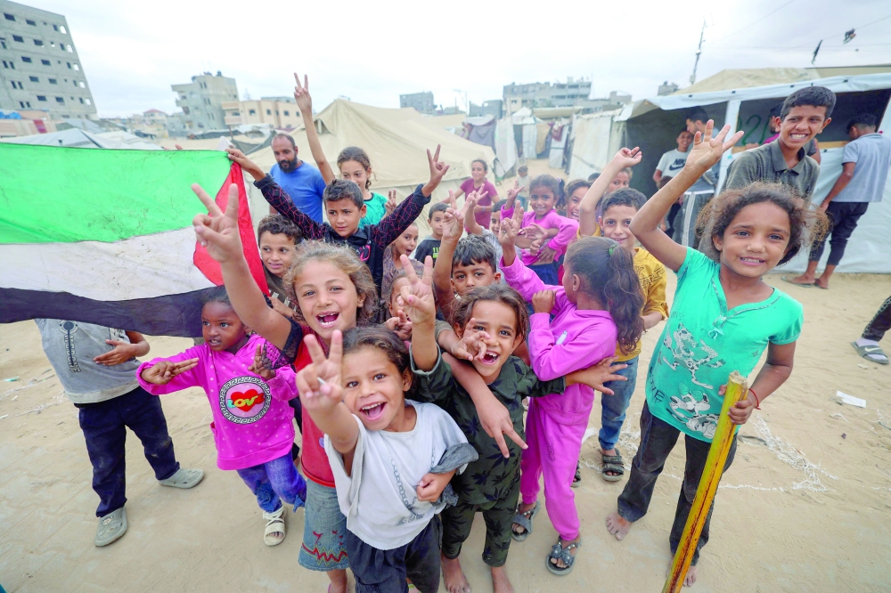 Palestinian children celebrate at a camp for displaced people in Nuseirat in the central Gaza Strip, following news of a new Gaza ceasefire deal. — AFP