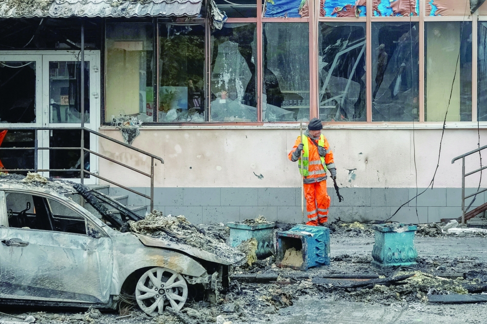 A municipal service worker cleans up debris near buildings damaged during a strike, in the town of Brovary, Kyiv. — Reuters