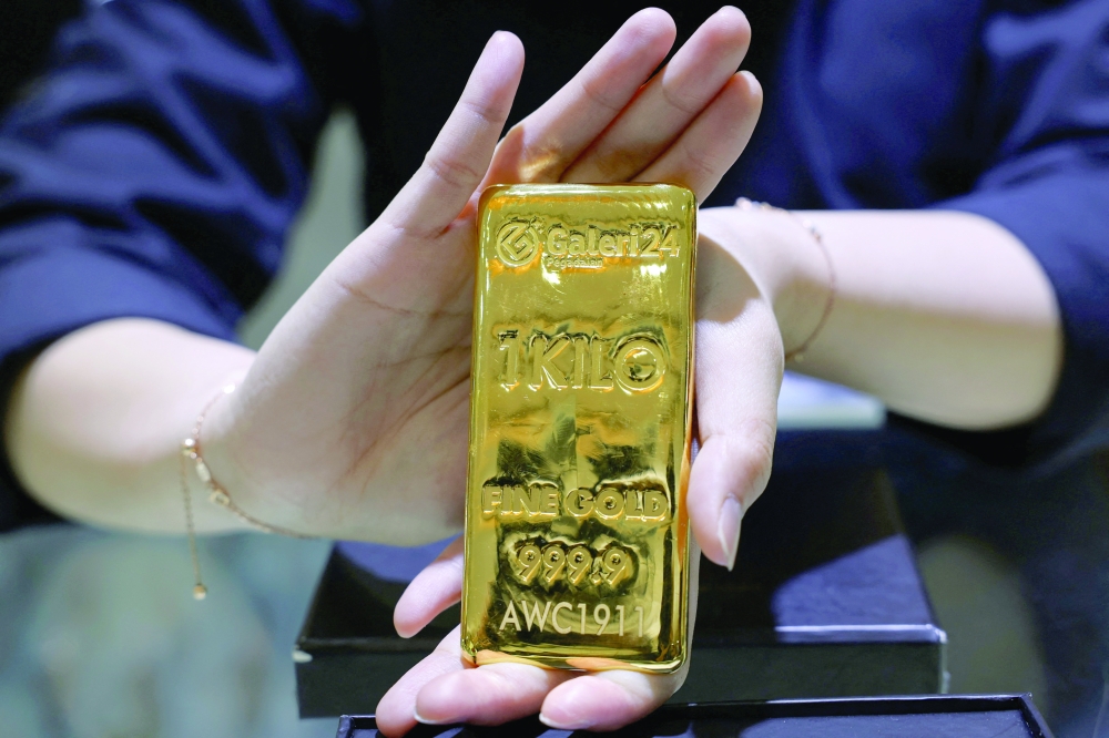 A sales woman shows a one-kilogramme gold bar at the Galeri 24 gold and jewellery shop in Jakarta on Friday. — Reuters