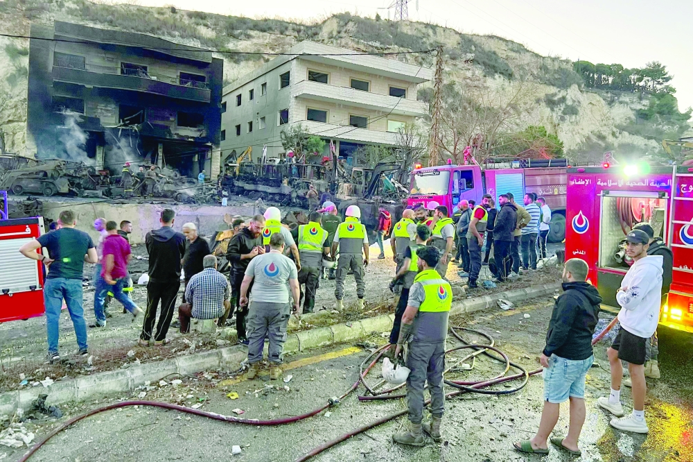 Rescuers and first-responders stand outside a damaged building, in southern Lebanon. — AFP