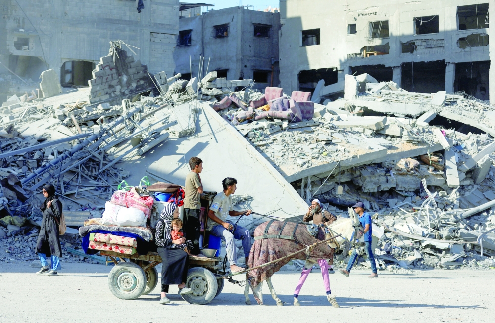 Palestinians ride on an animal-drawn cart among rubble, following Israeli forces' withdrawal from the area, amid a ceasefire between Israel and Hamas in Gaza, in Gaza City. - AFP 