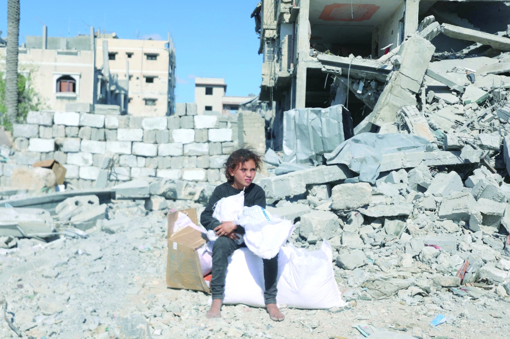 A Palestinian girl sits by aid parcels after aid trucks entered from the Karem Abu Salem crossing, in Khan Yunis in the southern Gaza Strip on Sunday. - AFP