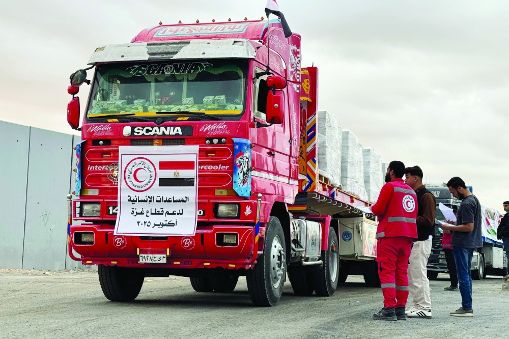 Members of the Red Crescent stand near a truck loaded with humanitarian aid on the Egyptian side of the Rafah crossing, waiting to get access to the Gaza Strip. — AFP