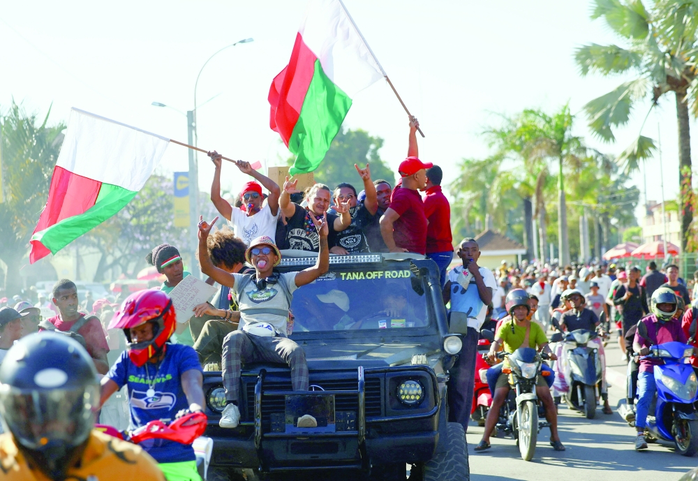 A pickup truck drives with occupants waving flags after the military joined protesters, in Antananarivo, Madagascar. — Reuters