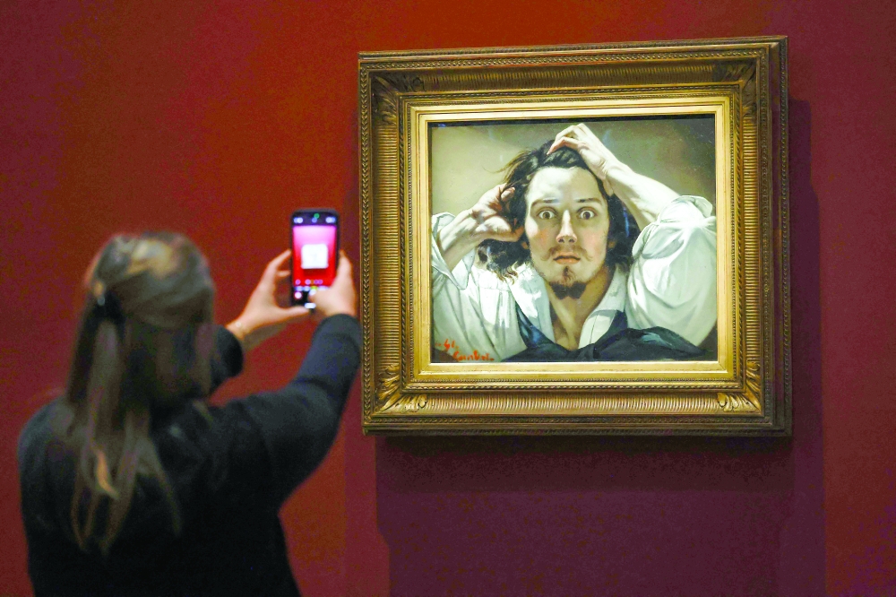 An attendee takes a photograph with a mobile telephone of Gustave Courbet's oil-on-canvas "The Desperate Man" exhibited at the Musee d'Orsay, in Paris. — AFP 