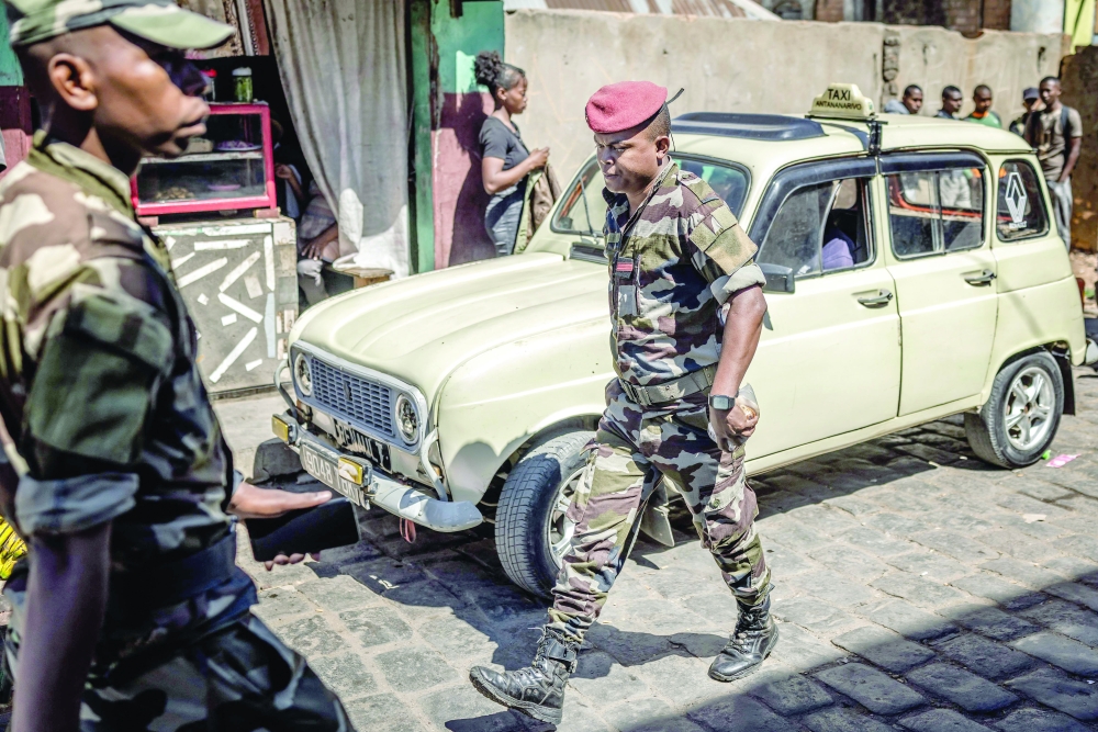 Members of Madagascar Army CAPSAT unit walk past an old taxi near the CAPSAT base, in Antananarivo. — AFP