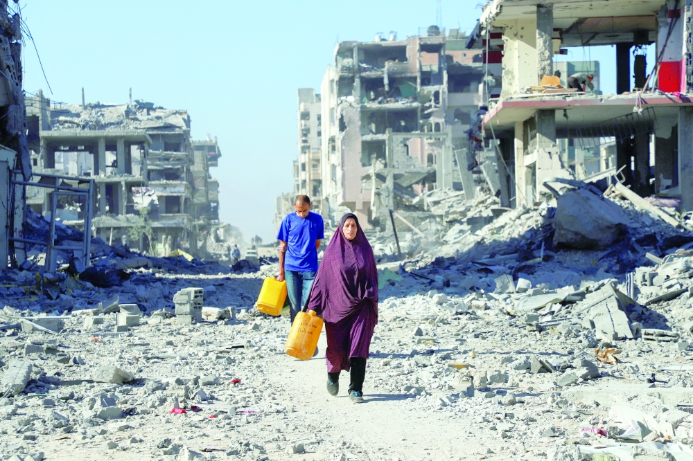 Palestinians walk past the rubble of destroyed buildings, amid a ceasefire between Israel and Hamas, in Gaza City. — Reuters