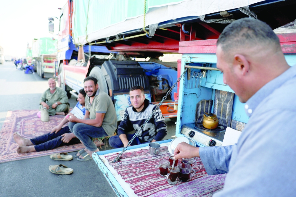 A driver prepares tea next to trucks loaded with humanitarian aid from Egypt's National Alliance For Civil Development Work (NACDW) near the Rafah border crossing on Thursday. — AFP