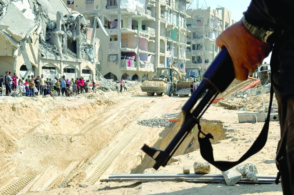 A Hamas fighter stands guard, as heavy machinery operates at the site where searches are underway for the bodies of hostages killed after being seized by Hamas during the October 7, 2023 attack, in Khan Yunis on Friday. — Reuters