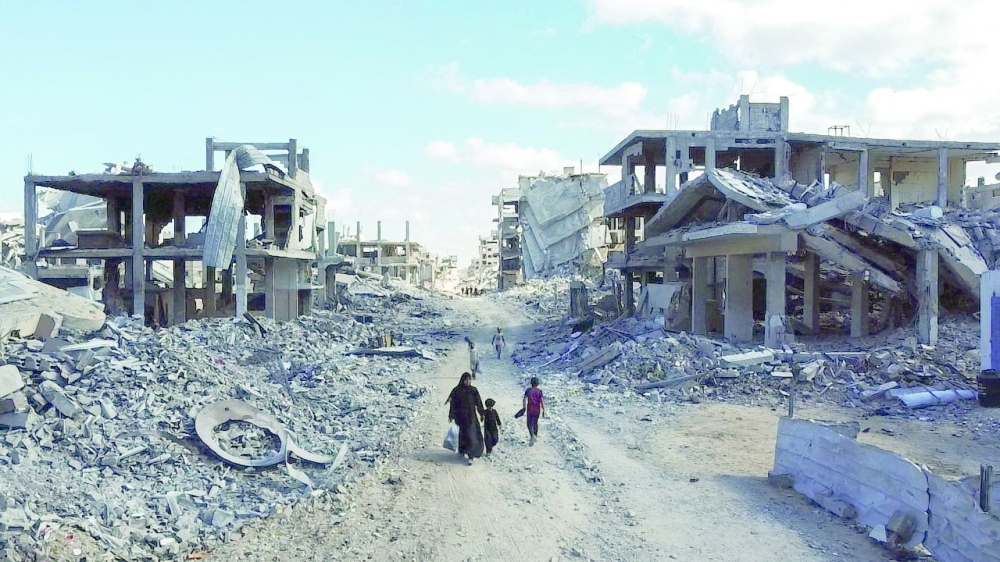 A drone view shows people walking through a destroyed residential neighbourhood, following the withdrawal of the Israeli forces from the area, amid a ceasefire between Israel and Hamas in Gaza, in Gaza City.