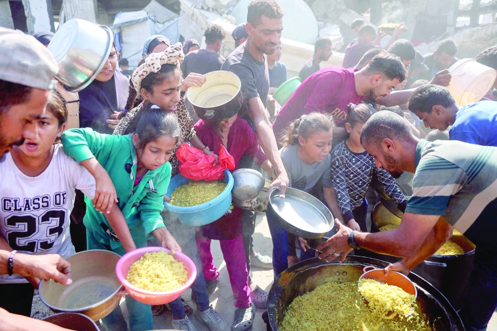 Displaced Palestinians gather to receive food portions in the Zeitoun neighbourhood of Gaza City. — AFP