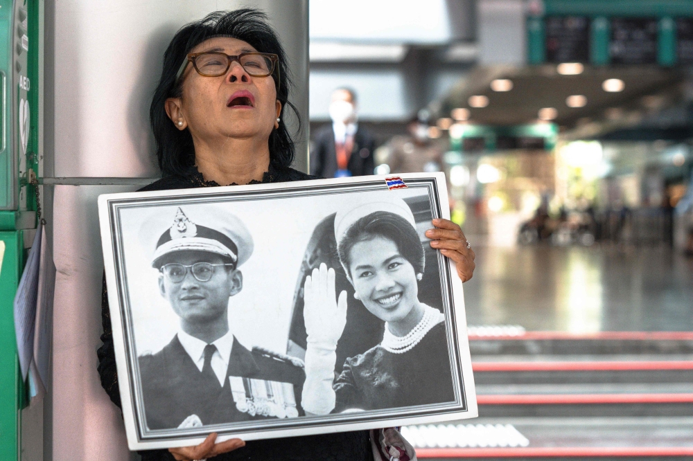 Thai mourner Kanjana Malaithong holds a portrait of Thailand's former queen Sirikit and Thai King Bhumibol Adulyadej 