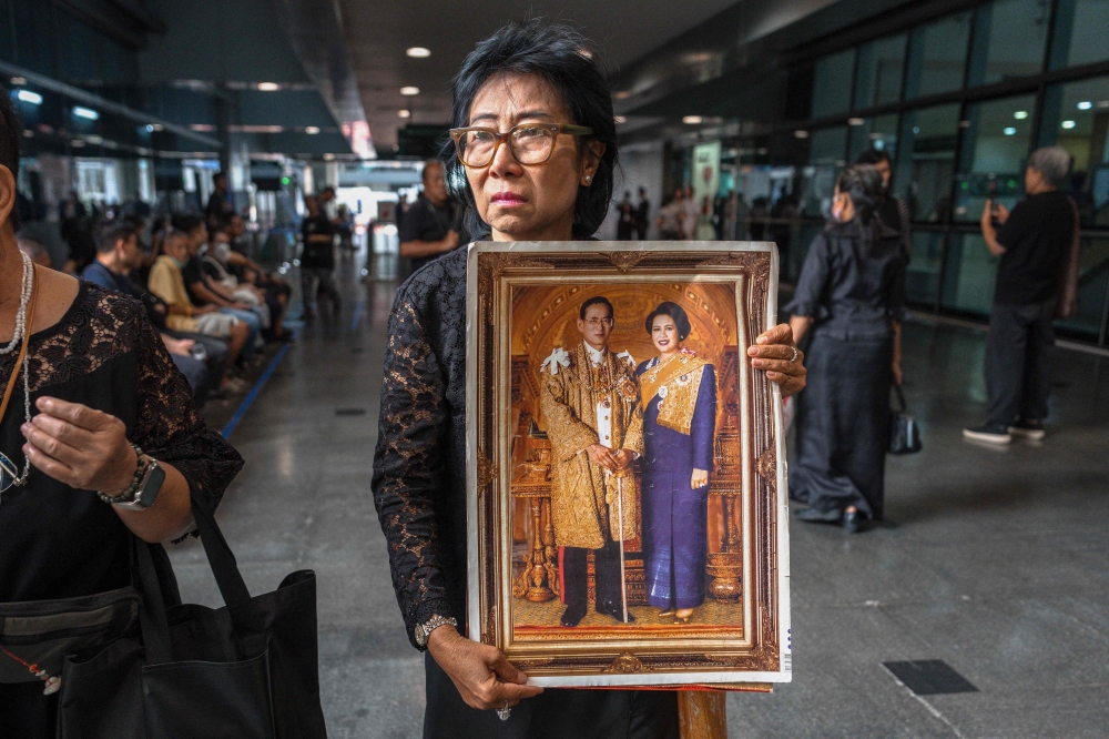 Thai mourner Kanjana Malaithong holds a portrait of Thailand's former queen Sirikit and Thai King Bhumibol Adulyadej 