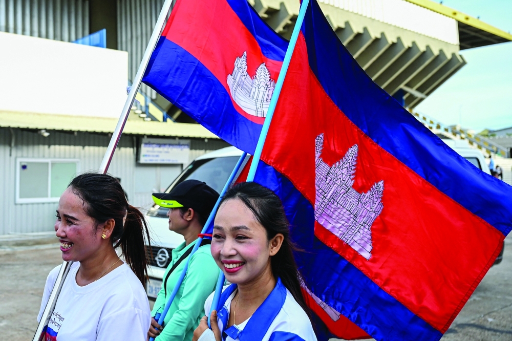 Women carry national flags to celebrate the signing of a ceasefire agreement between Cambodia and Thailand in Kuala Lumpur, at the National Olympic Stadium in Phnom Penh. - AFP