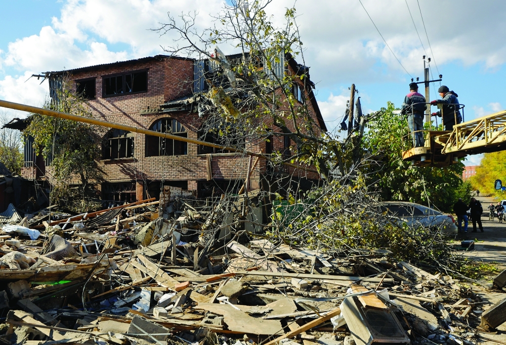 Workers fix wires in front of a damaged house following what Russian-installed authorities described as an overnight Ukrainian missile strike in the Donetsk region. — Reuters