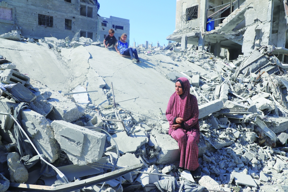 Displaced Palestinian woman Amal Alyan and her children sit on the rubble of homes destroyed during Israeli strikes, amid a ceasefire between Israel and Hamas, at Al Shati camp, in Gaza City. — Reuters