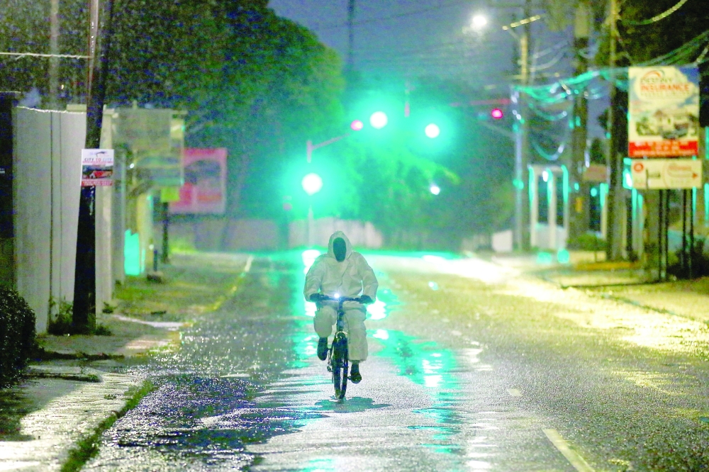 A man wearing a protective suit cycles on a street, as Hurricane Melissa approaches, in Kingston on Tuesday. — Reuters