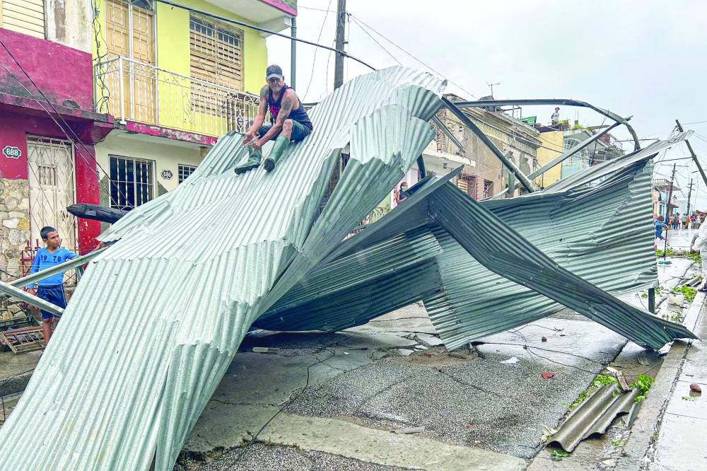 A resident sits on part of the roof of his house, damaged by Hurricane Melissa, in Santiago de Cuba on Wednesday. — AFP 