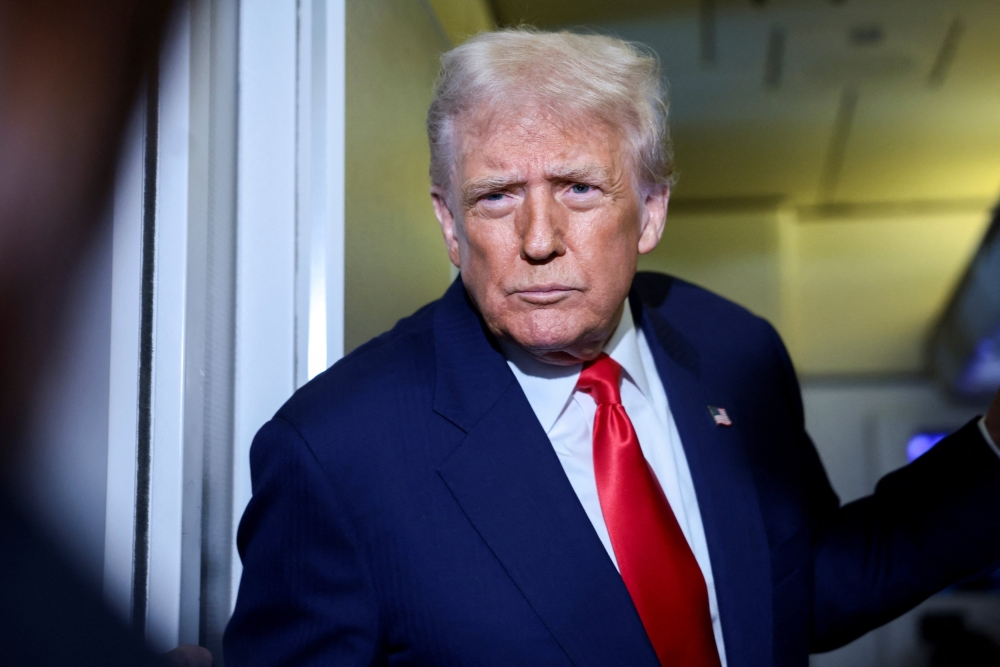 U.S. President Donald Trump speaks to members of the media on board Air Force One en route to the U.S