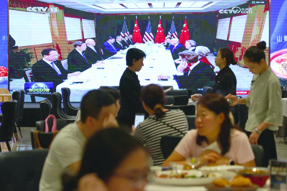 A screen shows news footage of the bilateral meeting between Chinese President Xi Jinping and US President Donald Trump on the sidelines of the APEC summit in South Korea's Busan, at a restaurant in Shenzhen, Guangdong province. - Reuters