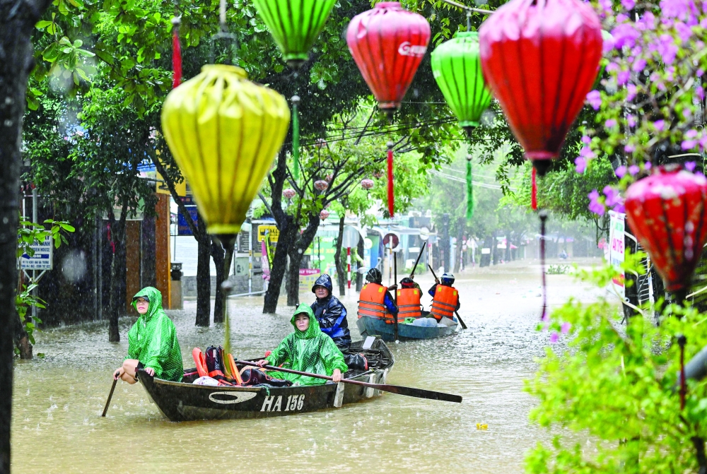 People navigate a flooded street on boats during heavy rains in Hoi An on October 30, 2025. Record heavy rains and flooding in central Vietnam this week have killed 35 people, disaster management officials said on November 2, 2025, with five more still missing in the deluge. (Photo by Nhac NGUYEN / AFP)