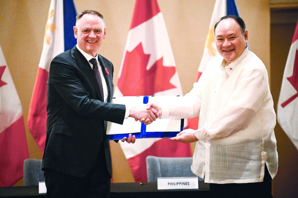 Philippines' Secretary of National Defence Gilberto Teodoro (R) shakes hands with Canadian Minister of Defence David McGuinty, in Manila. — AFP
