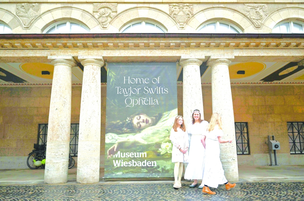 Fans of US singer-songwriter Taylor Swift pose next to a placard with the title 'Home of Taylor Swift's Ophelia' outside the Museum in Wiesbaden, western Germany, where the painting 'Ophelia' by German artist Friedrich Heyser is displayed for a short guided tour for the so-called Swifties. - AFP
