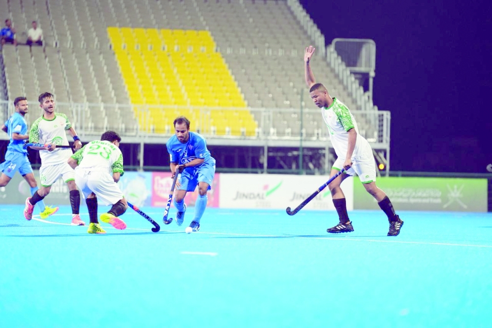 Qurayat and Al Amerat players fight for the ball at the Hockey Oman Stadium.