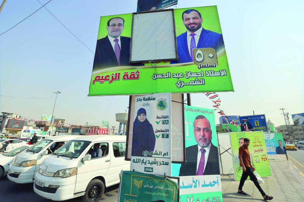 A man walks past electoral campaign posters ahead of Iraq's parliamentary elections in central Baghdad. — AFP