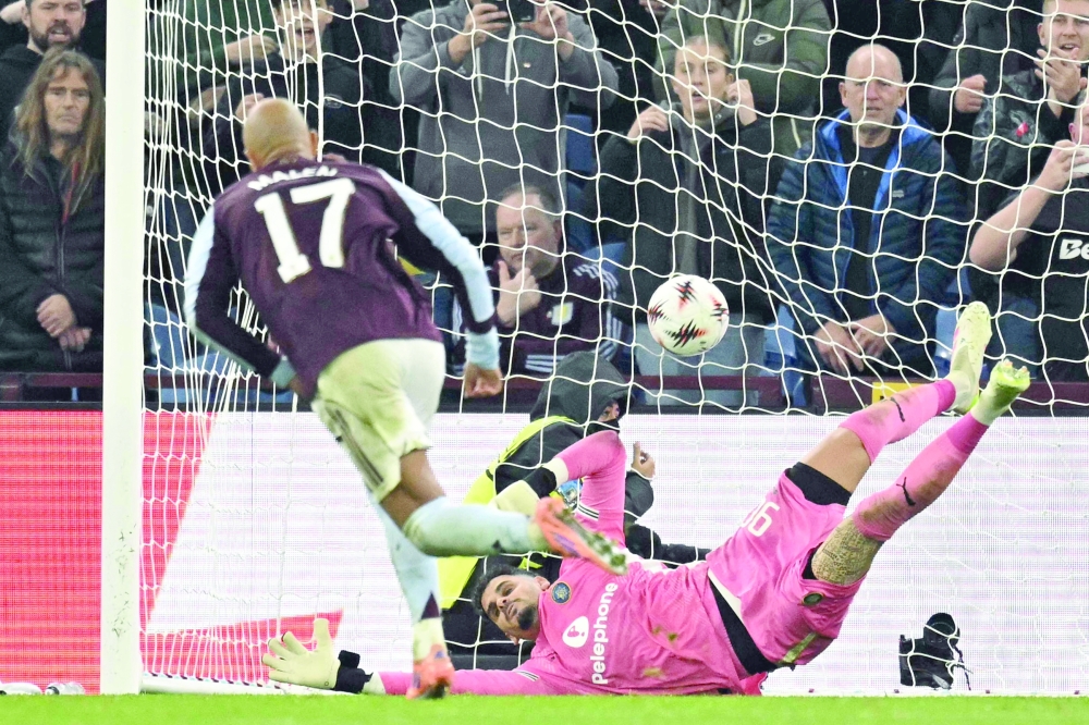 TOPSHOT - Aston Villa's Dutch defender  #17 Donyell Malen (L) slots the ball past Maccabi Tel Aviv's Israeli goalkeeper #90 Roi Mishpati (R) from the penalty spot to score their second goal for 2-0 during the UEFA Europa League league-stage football match between Aston Villa and Maccabi Tel Aviv at Villa Park in Birmingham on November 6, 2025.  (Photo by Oli SCARFF / AFP)
