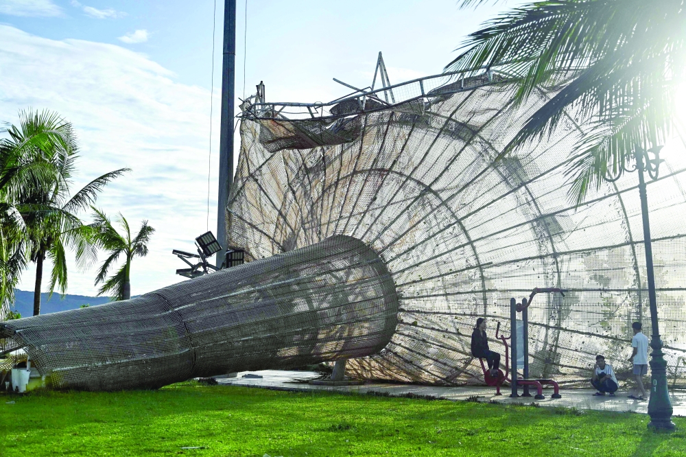 People rest near a structure, damaged by typhoon Kalmaegi, in the Quy Nhon area of Gia Lai province, central Vietnam. — AFP
