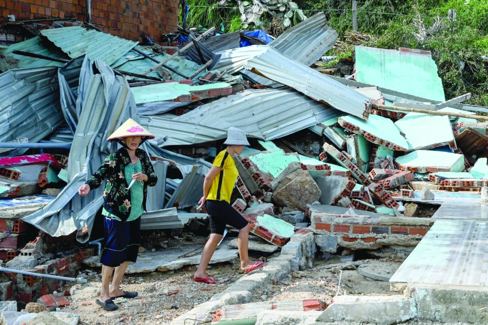 Residents walk over the debris of a structure destroyed in high winds in Nhon Hai fishing village near Quy Nhon in the aftermath of Typhoon Kalmaegi in Gia Lai province, central Vietnam. — AFP