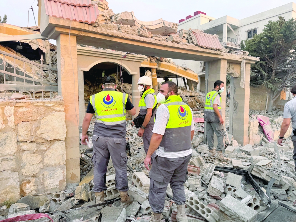 Members of civil defence stand on rubble at a damaged site after Israeli strikes, in Tayr Debba, southern Lebanon. — Reuters