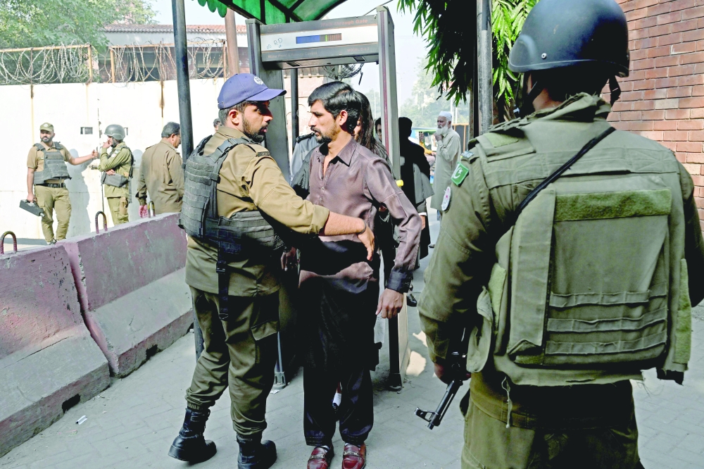A policeman frisks a man at court entrance in Lahore. — AFP