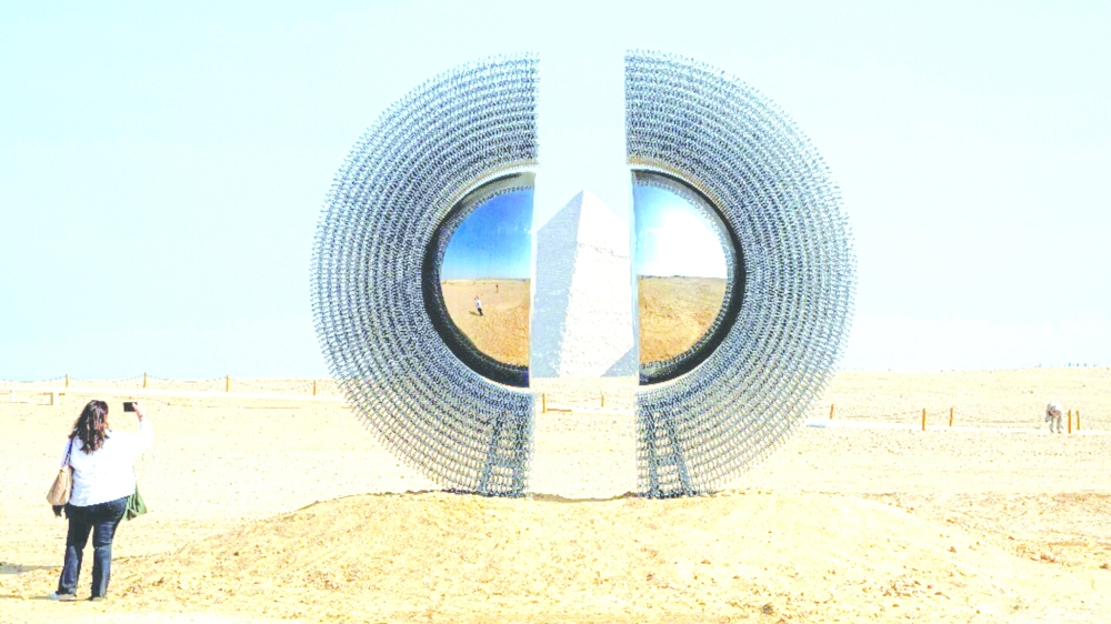 A woman takes a picture of the art installation "The Shen" by artist by Mert Ege Kose during the fifth edition of the "Forever is Now" art exhibition by Art d’Egypte at the Giza pyramids necropolis.