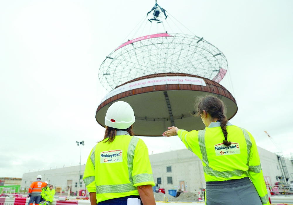Workers stand near a 245-tonne domed roof lifted by the land crane 'Big Carl' before placing on the second reactor building at the Hinkley Point C nuclear power station near Bridgwater, Britain. - Reuters 