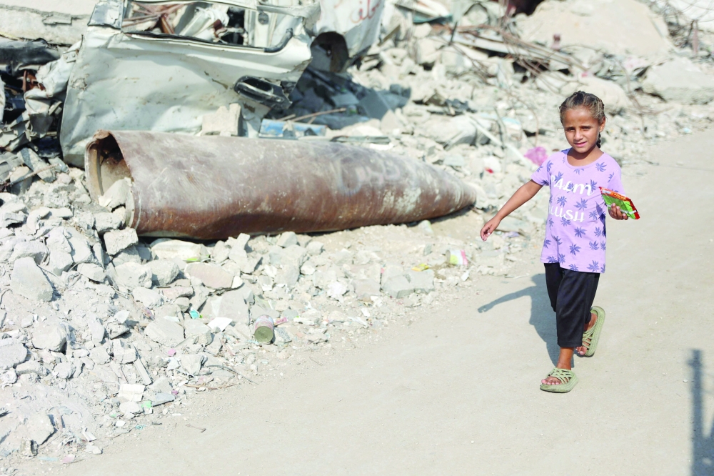 A Palestinian girl walks past an unexploded missile in the Al Rimal neighbourhood of Gaza City. - AFP