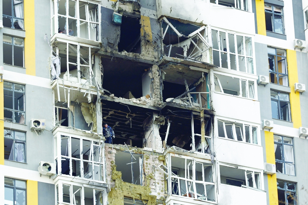 A resident removes debris inside of an apartment building hit during overnight Russian drone and missile strikes in Kyiv, Ukraine. — Reuters