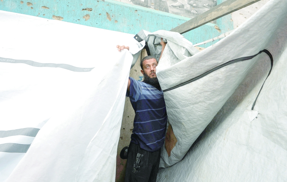 A man repairs a tent on a rainy day in Gaza City on Friday. — Reuters