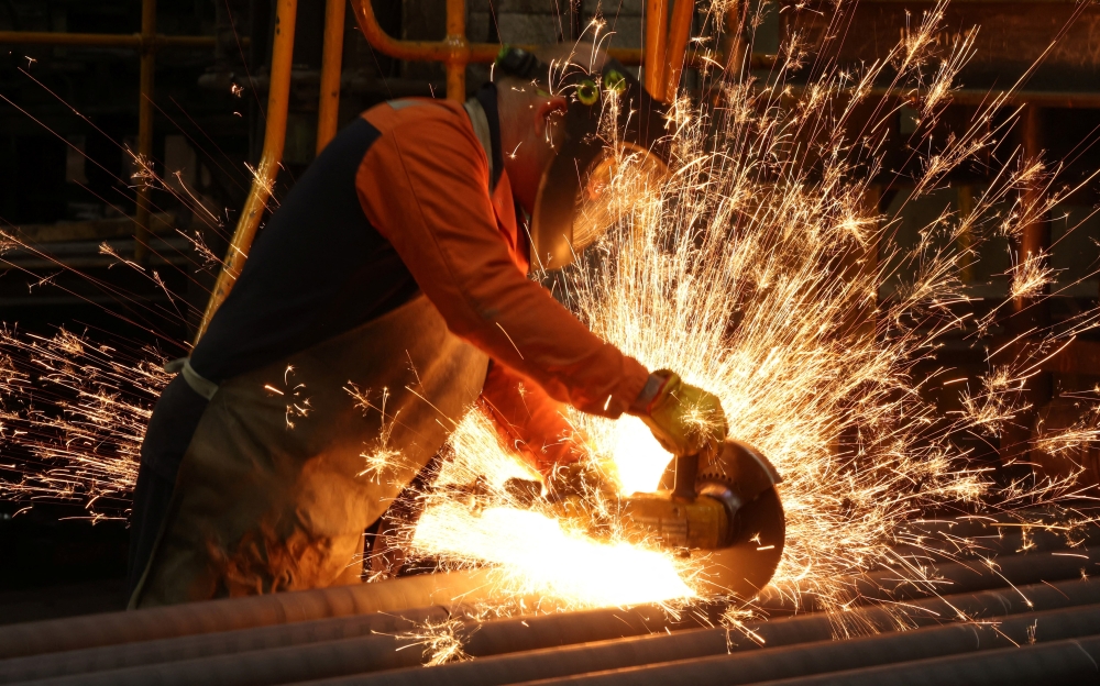 A worker cuts newly manufactured bars of steel at a foundry in Chesterfield, Britain. Image for illustration only. — Reuters
