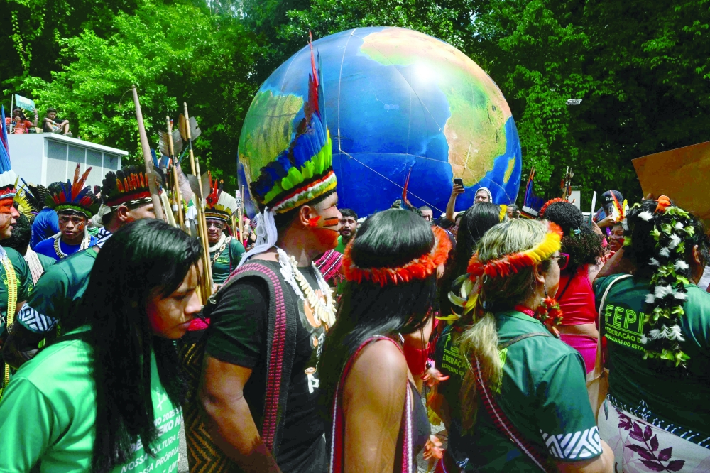 Indigenous people walk past a giant inflatable globe during the "Indigenous People Global March" in Belem, Brazil. — AFP