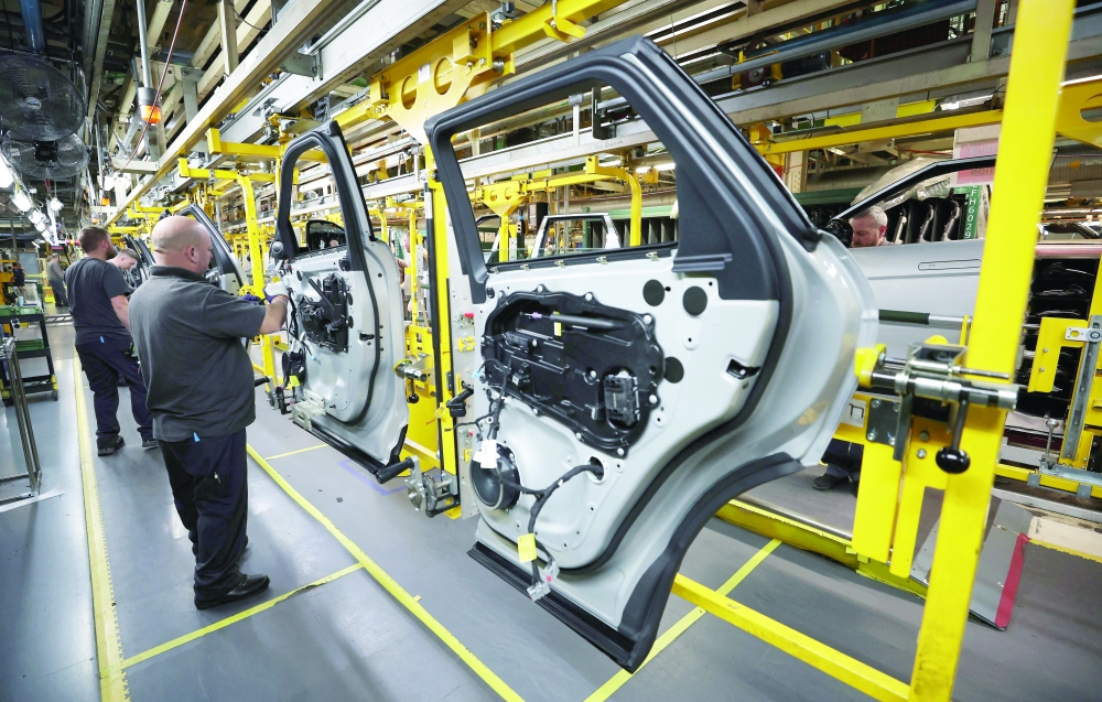 Staff members assemble door panels on the production line at a car factory in Liverpool, Britain. — Reuters